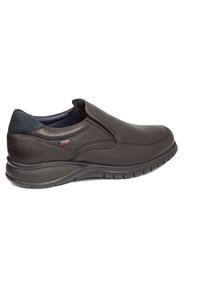 Zapato marrón de cuero tipo slip-on con punta redonda, suela de goma texturizada y acentos en azul marino en el talón y los paneles elásticos laterales.