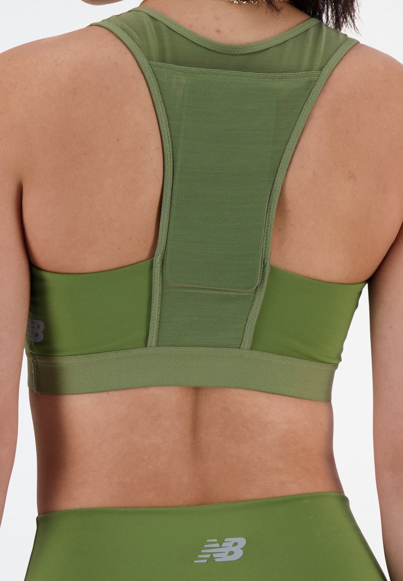 Grüner Sport-BH mit Racerback-Design, strukturiertem Netzpanel auf der Rückseite und elastischem Band; mit grauem New Balance-Logo.