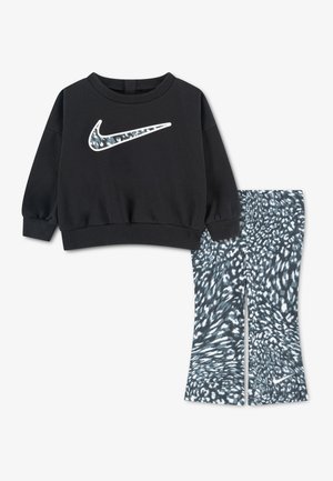 Zwarte longsleeve trui met een patroon van de Nike Swoosh en bijpassende zwart-wit gevlekte legging met klein logo op het been.