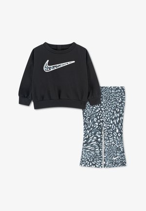 Czarna bluza z długim rękawem z wzorzystym logo Nike i pasujące czarno-białe legginsy w kropki z małym logo na nodze.
