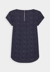 Blouse navy à manches courtes avec un motif blanc, bas arrondi et fermeture éclair au dos. Tissu léger avec une texture lisse.