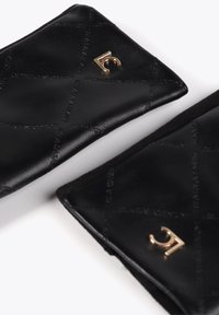 Černé kožené doplňky s prošívaným vzorem, zvýrazněné zlatým logem. Hladký povrch s jemným brandingem po celém povrchu.