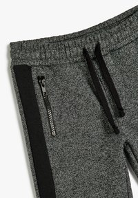 Gray athletic joggers with a textured fabric, featuring a black side panel and zippered pocket. Includes a drawstring waistband for adjustability.