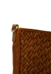 Angolo di una borsa in pelle marrone con motivo in pelle intrecciata e dettaglio in ottone sull'attacco della tracolla.