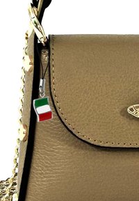 Gouden handtas met textuur en een klep sluiting, voorzien van een kleine Italiaanse vlag charme en een kettingband, geaccentueerd met gouden hardware.