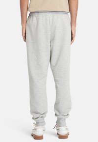 Grå sweatpants med elastisk talje, tapered ben og ribbede manchetter, lavet af blødt bomuldsstof. Bæres med hvide sko.