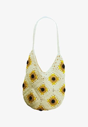 Sac à main crème au crochet avec des motifs de tournesol jaunes et bruns et une bandoulière unique.