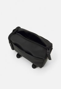 Borsa rettangolare nera realizzata in nylon liscio con chiusura a zip, doppie tasche laterali e due piedini rotondi per stabilità.