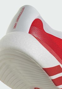 Chaussure de sport rouge avec une tige texturée, des accents blancs et une semelle épaisse à rainures. "HYPERBOOST EDGE" est embossé sur la zone du talon.