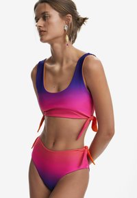 Ensemble de bikini deux pièces avec un dégradé allant du violet au rose. Le haut a un décolleté arrondi et des ornements noués ; le bas taille haute comporte également des liens.