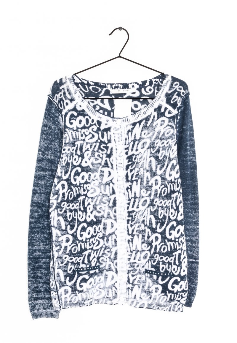 Cardigan en maille bleu marine et blanc à manches longues avec texte manuscrit blanc sur toute la surface, incluant « Good », « Promise » et « Bye », sur un cintre noir.
