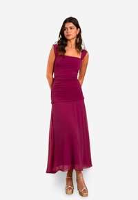 Langes, lila Kleid mit einem figurbetonten Oberteil und ausgestellt Rock. Weicher, dehnbarer Stoff, kurze Ärmel und schlichte Raffung an der Taille.