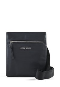Crna crossbody torba sa teksturiranim vanjskim dijelom, prednjim džepom na zip, i logotipom brenda. Uključuje pletenu naramenicu za nošenje.