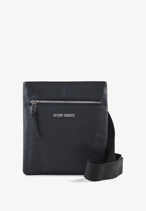 Borsa a tracolla nera con un esterno testurizzato, tasca frontale con zip e logo del marchio. Include una tracolla intrecciata per il trasporto.