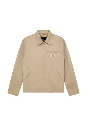 Giacca beige con cerniera, colletto appuntito, due tasche laterali, una tasca sul petto con cerniera e una piccola toppa con logo rosso e bianco.