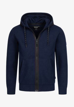 Felpa con zip di colore navy, con cappuccio regolabile a stringa, due tasche frontali, polsini a costine e tessuto a maglia testurizzato. Dettaglio nella zip nera centrale.