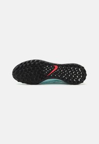 Semelle extérieure noire avec un motif texturé, dotée d'un intermédiaire turquoise et d'un accent logo rouge. Accent sur la traction et la durabilité du design.