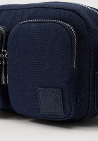 Die marineblaue Stofftasche verfügt über eine strukturierte Oberfläche, Reißverschlussfächer und ein Markenpatch mit dem eingeprägten "MAX&Co.".