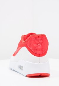 Sneaker Nike Air rouge et blanc vu de l'arrière, montrant le talon rouge avec le logo Nike Air et la semelle blanche avec le coussin d'air visible.