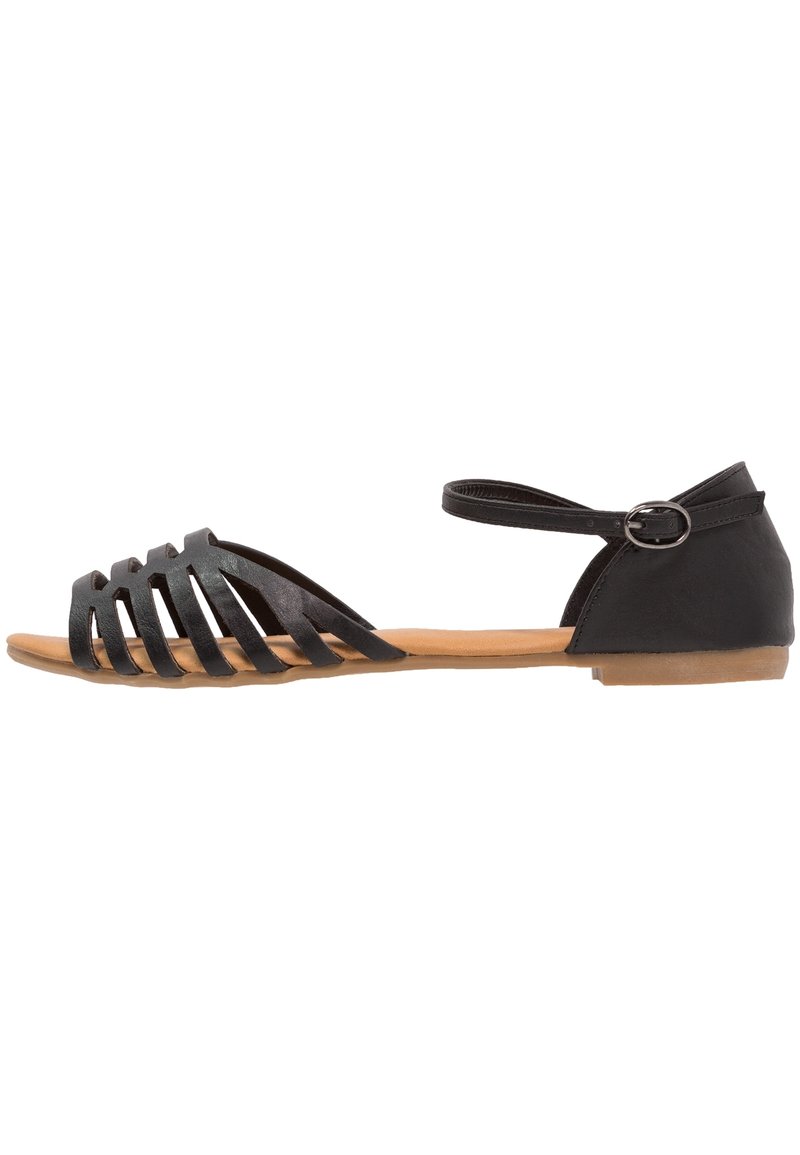 Black sandal with a strappy design, features a flat brown sole, ankle strap with buckle, and a smooth material texture.