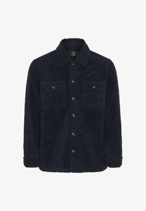 Námorná fleecová košeľa s šušťakovým povrchom, s dvoma prednými vreckami, hnedými gombíkmi a čiernymi akcentmi na pleciach.