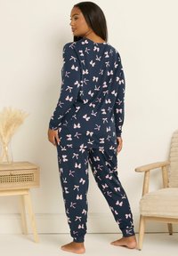 Granatowy komplet piżamowy wykonany z miękkiego materiału, z wzorem drobnych różowych kokardek. Zawiera długie rękawy oraz dopasowane spodnie z mankietami.