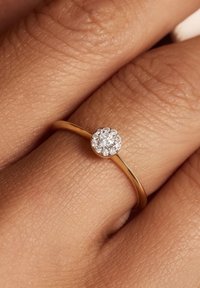 Bague en or avec un fin anneau présentant un cluster de petits diamants ronds sur un sertissage surélevé, mettant en valeur son éclat et sa texture.