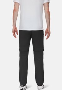 Sorte, af-zipbare vandrestøvler med en glat tekstur, lige ben-design og synlige syninger. Bæres med en hvid T-shirt og sneakers.