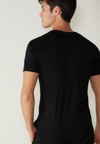Schwarzes T-Shirt mit kurzen Ärmeln aus weichem Material und Rundhalsausschnitt. Glatte Textur, minimalistisches Design und keine sichtbaren Muster oder Akzente.