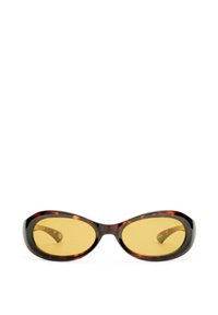 Lunettes de soleil en écaille de tortue avec des verres jaunes, de forme ovale et finition brillante. Présentent une monture épaisse et un branding subtil sur l'intérieur de la branche.