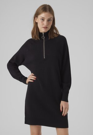 Abito nero in maglia con collo alto e dettaglio della cerniera in argento. Presenta polsini e orlo a costine, vestibilità comoda e texture morbida.