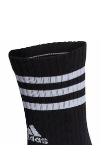 Schwarze Sportsocke mit geripptem Muster, ausgestattet mit drei horizontalen weißen Streifen und einem weißen Logo im Knöchelbereich.