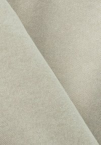 Tissu beige clair présentant un tissage texturé, avec des lignes diagonales distinctes créant une surface douce et durable.