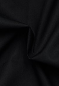 Tessuto nero con una superficie liscia, caratterizzato da sottili motivi a diagonale e una leggera lucentezza, disposto in pieghe morbide.