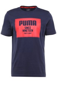 Mörkblå T-shirt i bomull med rund halsringning. Har en stor röd grafisk tryck med texten "PUMA SEDAN NITTONHUNDRA FORTY ÅTTA."