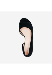 Black suede open-toe shoe with a low curved cutout design, featuring a smooth inner sole and a subtle embossed brand logo on the bottom.