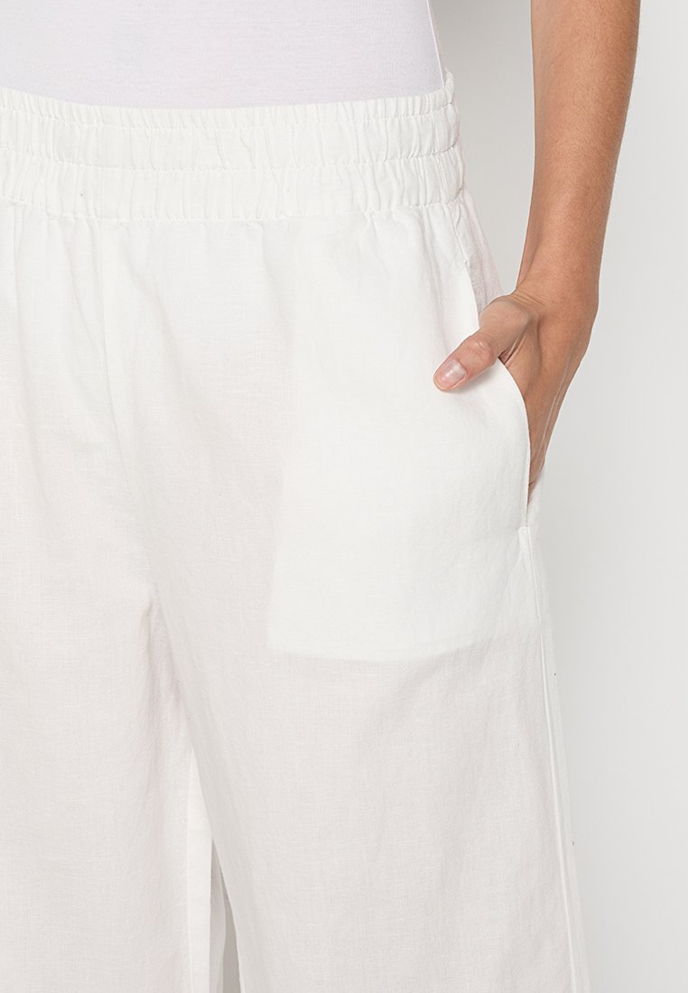 Weiße Leinenhosen mit einem elastischen Bund und zwei Seitentaschen. Der Stoff hat eine leicht strukturierte Oberfläche und bietet eine lässige Passform.
