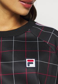 Černá mikina se síťovým vzorem v červené a bílé barvě, s kulatým výstřihem a vyšívaným logem v levém dolním rohu.