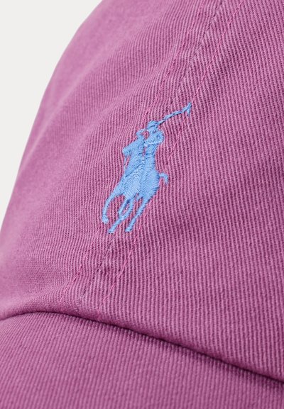 Rožinė medvilninė kepurė su mėlynai siuvinėti polo žaidėjo ant arklio logotipu, su tekstūruota medžiaga ir matomais siuvinėjimo detalėmis.