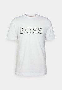 Biała bawełniana koszulka z wyraźnym, wypukłym czarnym logo "BOSS" na przodzie, z krótkimi rękawami i okrągłym dekoltem.