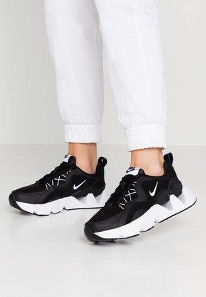 Sorte atletiksko med en tekstureret overdel, hvide accenter og en chunky sål. Har fremtrædende logo og kontrasterende snørebånd.