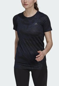 Camisa atlética negra con un patrón de estampado animal texturizado en azul oscuro, mangas cortas, escote redondo y un logo de Adidas en el pecho.