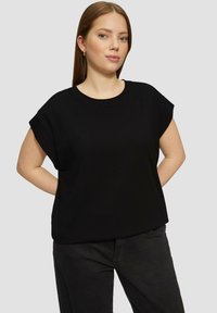 Zwarte katoenen T-shirt met korte mouwen, relaxed fit, ronde halslijn en een soepele textuur, gedragen met een donkere broek.
