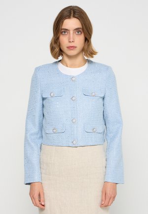 Giacca corta azzurro chiaro realizzata in tessuto strutturato, con bottoni rotondi argentati e due tasche frontali con patta. Maniche lunghe, scollatura rotonda.