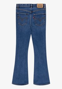 Jean flare en denim bleu avec une ceinture, deux poches arrière avec une couture en V, et une étiquette de marque à l'arrière. Texture lisse.