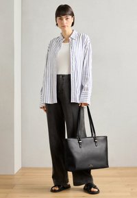 Schwarze Leder-Tote mit doppelten Schulterriemen; schlanker, rechteckiger Schnitt; glatte Textur; goldenes Logodetail auf der Vorderseite.