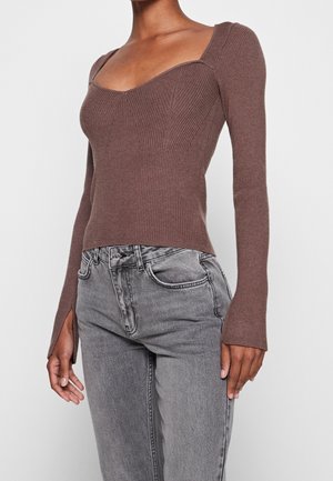 Haut marron à manches longues rayé avec décolleté carré et coupe ajustée. Assorti à un jean gris taille haute avec fentes sur les poignets.