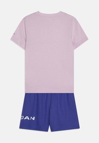 Roze katoenen T-shirt met korte mouwen, gecombineerd met blauwe mesh korte broek met witte merktext op het linkerbeen.