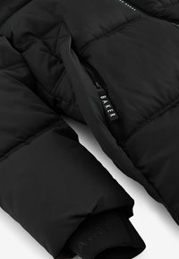 Sort pufferjakke med quiltet design, lynlåslomme med "BAKER" label og ribbet manchet. Blødt stof og mat finish.