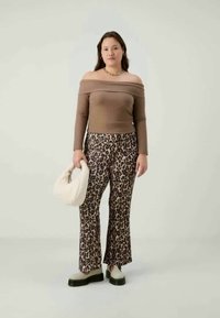 Ribbed brown off-shoulder top paired with leopard-print flared pants. Model holds a white bag and wears light-colored shoes with dark soles.
